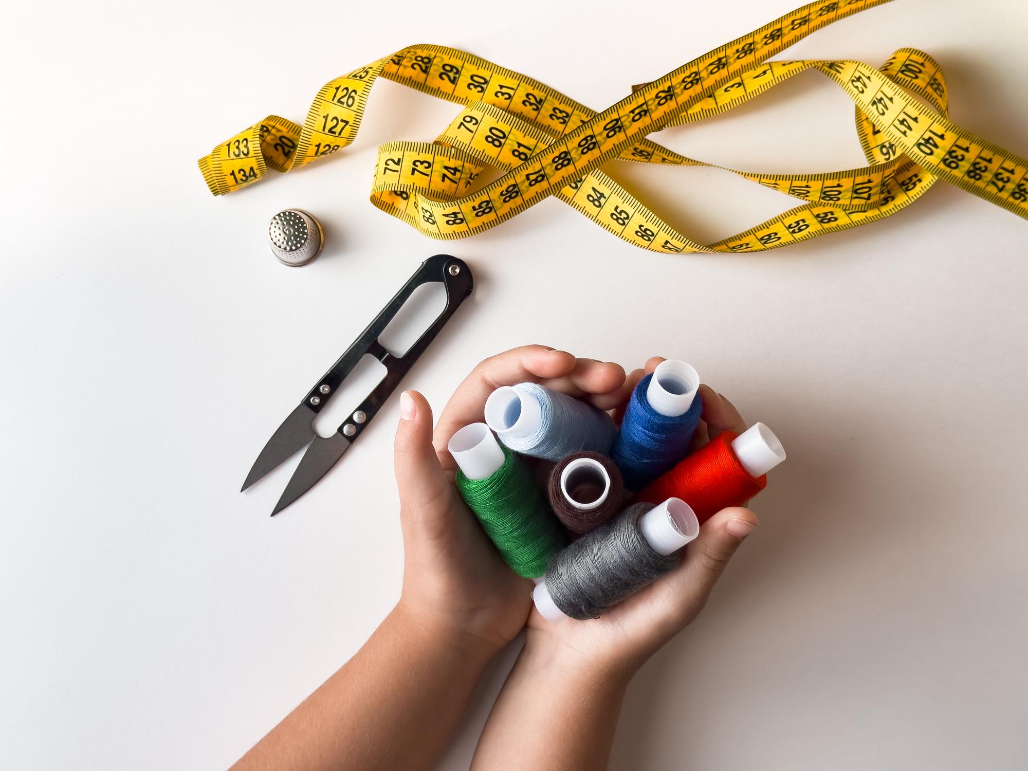 Founder holding embroidered textile with measuring tools